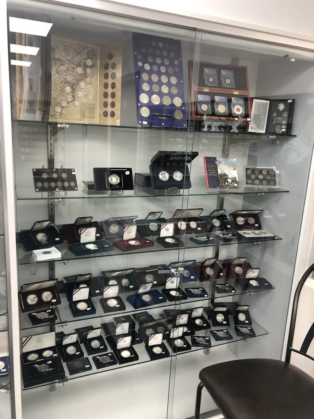 Tall glass case of US Mint silver proof sets and wartime nickel sets at Kansas Coin Connection