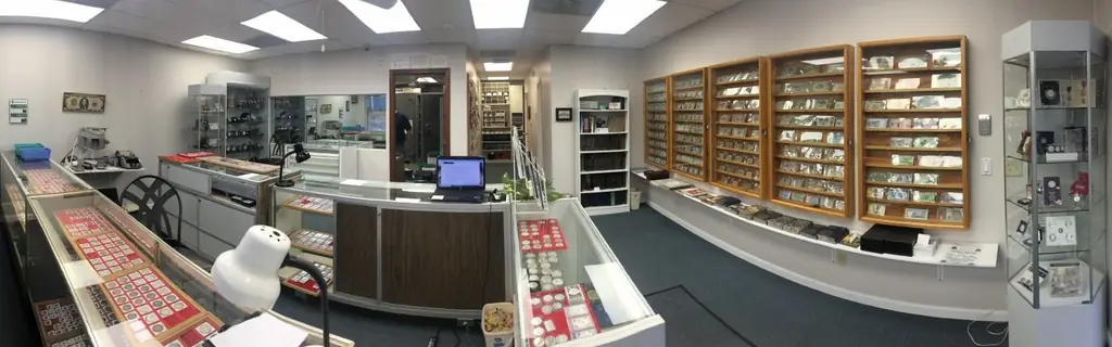 Inside Kansas Coin Connection: glass display counters and a wall of framed paper money cases